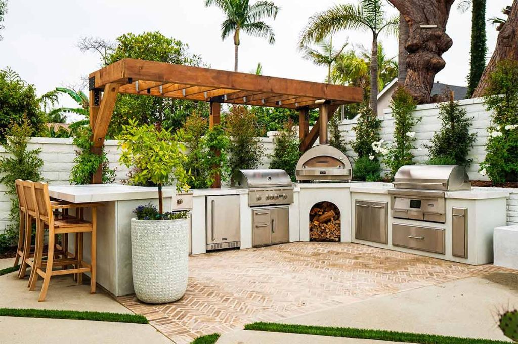 an outdoor kitchen space with bar, grill and prep area